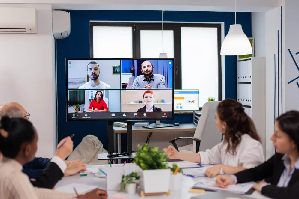 "Modern office meeting with a group attending a virtual video conference on advanced video conferencing solutions provided by Luminet India Pvt. Ltd.